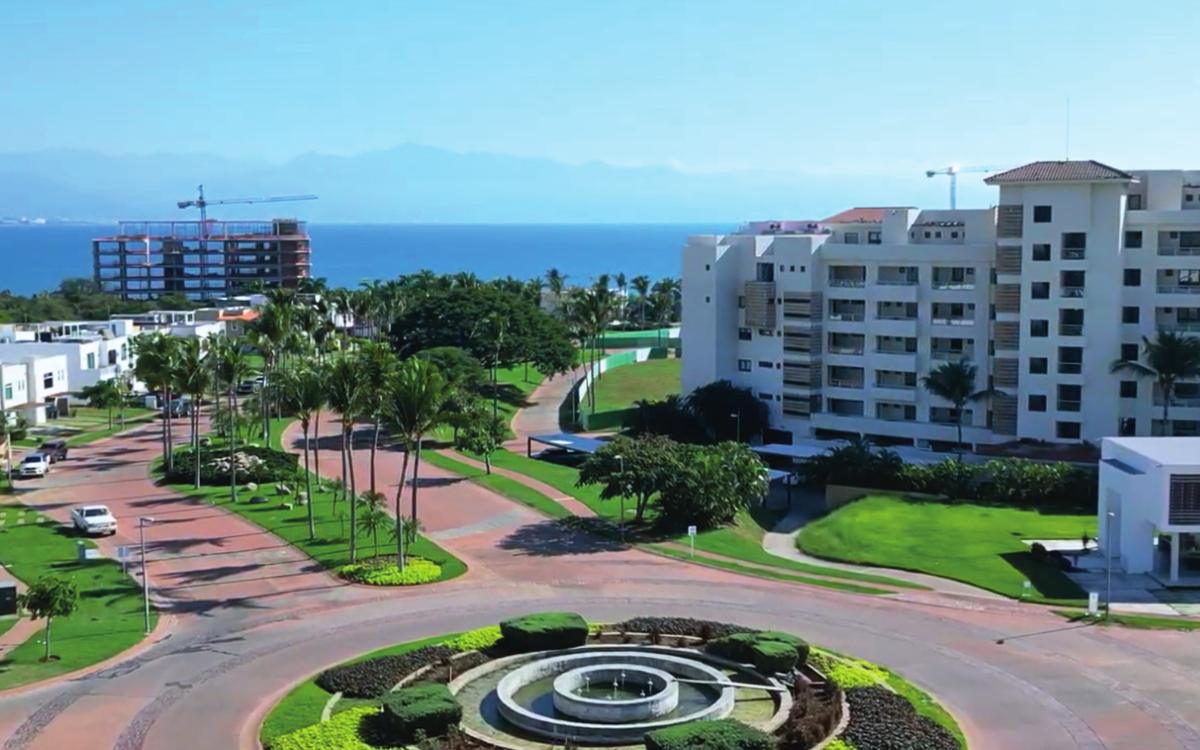 Acceso del residencial con glorieta ajardinada y vista al mar